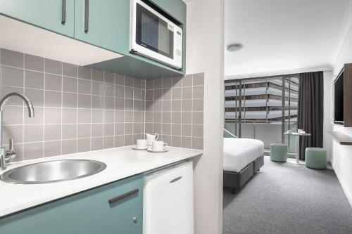 un bagno con lavandino e un letto in una camera di Mantra Chatswood a Sydney