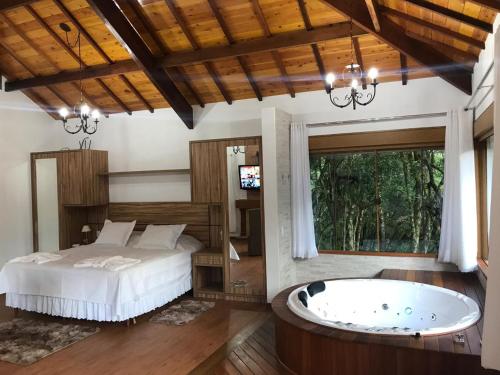 a bedroom with a bed and a bath tub at Chalés Recanto das Montanhas in Monte Verde