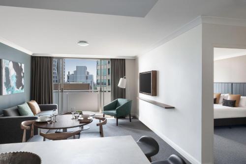 Habitación de hotel con zona de estar con cama y mesa. en Mantra Chatswood, en Sídney