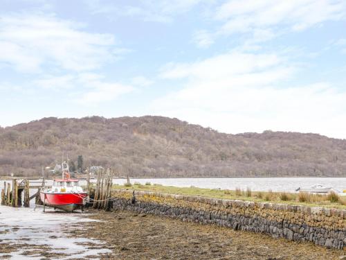 a boat is docked on a beach next to the water at The Knowe Lower in Taynuilt