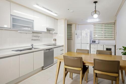 a kitchen with white cabinets and a wooden table and chairs at Home Fourest Resort Geoje in Geoje 