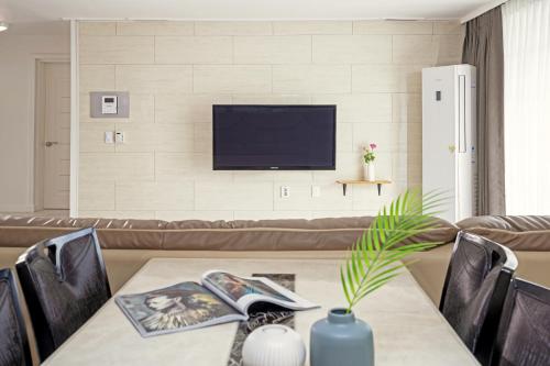 a living room with a table and a television at Home Fourest Resort Geoje in Geoje 