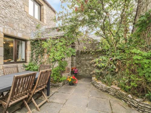 a patio with two benches and a table with flowers at Springarth Cottage in Morland