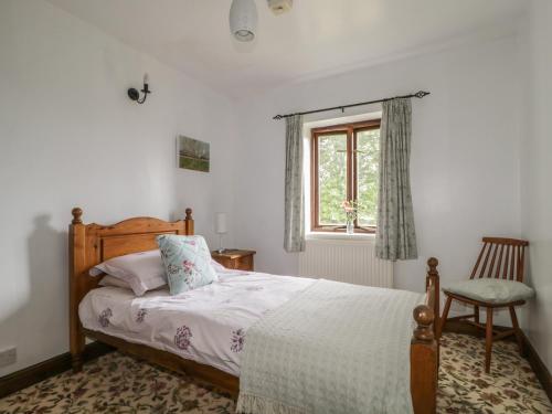a bedroom with a bed and a window and a chair at Springarth Cottage in Morland
