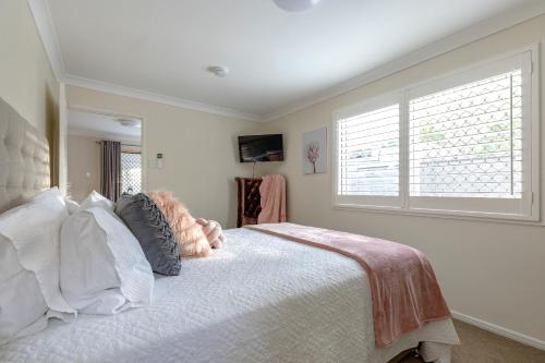 a bedroom with a white bed with a window at Woodford Gardens in Woodford