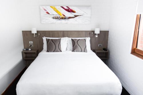 a bedroom with a white bed with two pillows at Bay Hotel Apartments in Hobart