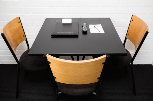 a black table with two chairs and a laptop on it at Bay Hotel Apartments in Hobart