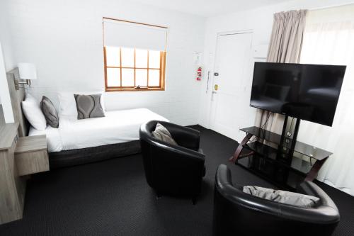 a hotel room with a bed and two chairs at Bay Hotel Apartments in Hobart