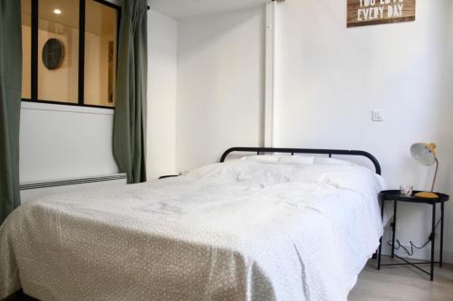 - un lit avec une couverture blanche dans l'établissement Atypical Apartment - Jardin Des Plantes, à Paris