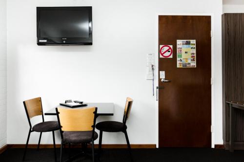 a room with a table and chairs and a television at Bay Hotel Apartments in Hobart
