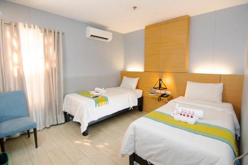 a bedroom with two beds and a blue chair at Viven Hotel in Laoag