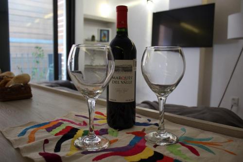 two wine glasses sitting on a table with a bottle of wine at Small cozy apartment in the historic center in Puebla