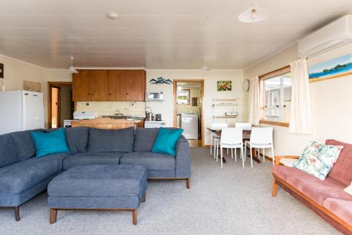 a living room with a blue couch and a kitchen at Dream View Waterfront Paihia in Paihia