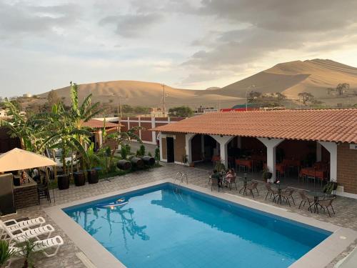 una piscina frente a una casa con montañas en el fondo en Huacachina Desert House, en Ica