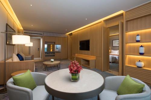 a hotel room with a table and chairs and a bedroom at Holiday Inn Kunshan Huaqiao by IHG in Kunshan