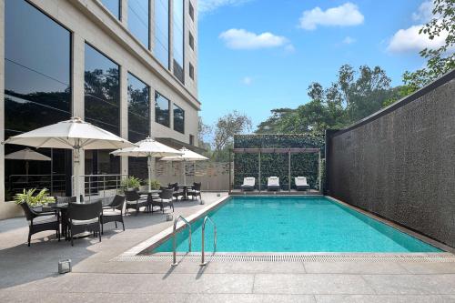 a swimming pool with chairs and umbrellas next to a building at Radisson Mumbai Andheri MIDC in Mumbai