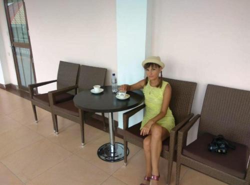 a woman sitting at a table with a cup of coffee at Aquamarine Inn in Cholpon-Ata