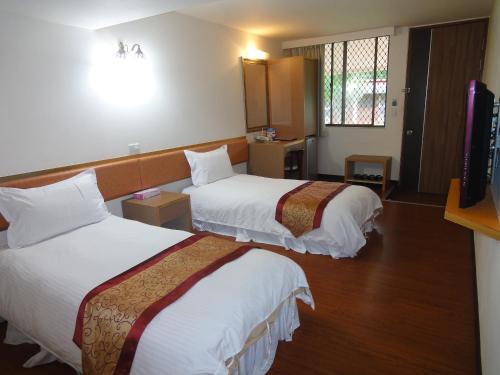 a hotel room with two beds and a television at Tsengwen Youth Activity Center in Nanxi