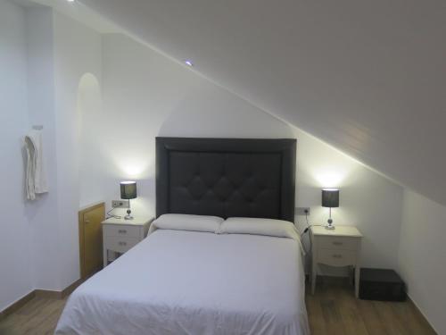 a bedroom with a large white bed with two night stands at Hotel Restaurante Boabdil in Otura
