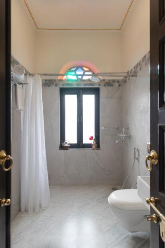 a bathroom with a toilet and a window and a sink at Tree of Life Inderpura Resort, Jhunjhunu in Jhunjhunūn