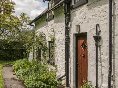 an old stone house with a wooden door at Penymaes in Chirk