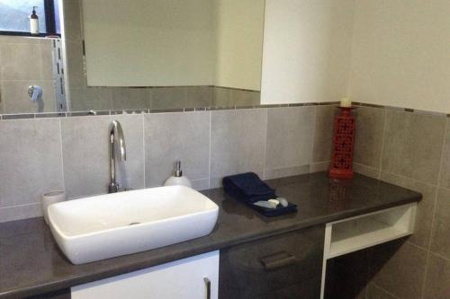 a bathroom counter with a sink and a mirror at Oceanview Apartment in Airlie Beach