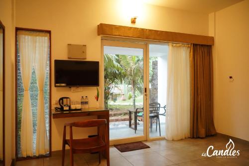 a living room with a television and a table with a chair at Le Candles Resort in Kozhikode