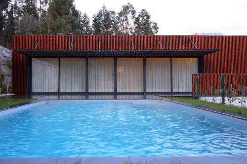 a swimming pool in front of a red building at Dantas Village in Moure