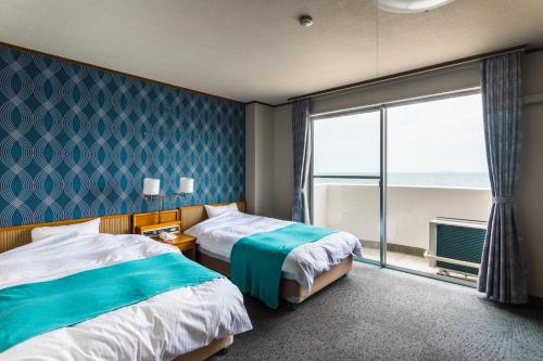 EtajimaにあるUminos Spa & Resortのベッド2台と大きな窓が備わるホテルルームです。