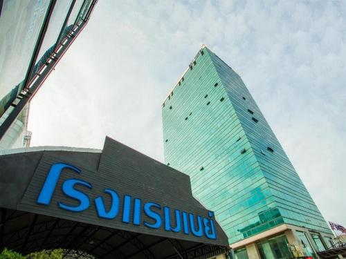 a tall glass building with a sign in front of it at Bay Hotel Srinakarin in Bangna