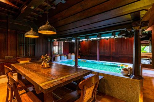 a dining room with a table and a swimming pool at Veena - By the Beach in Mararikulam