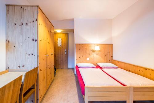 two beds in a room with wooden walls at Davos Youth Hostel in Davos