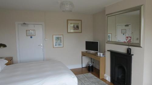 a bedroom with a bed and a television and a fireplace at The Lion Waddesdon in Waddesdon