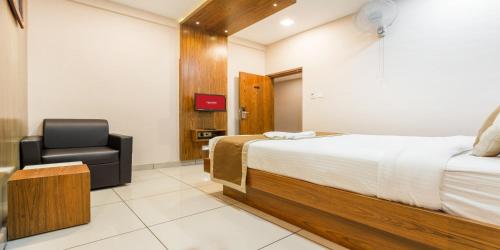 a hotel room with a bed and a chair at Nextel Inn, Calicut in Kozhikode
