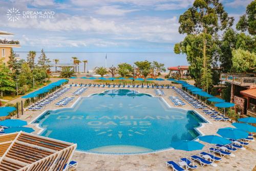 a large swimming pool with blue chairs and umbrellas at Dreamland Oasis Hotel Chakvi in Chakvi