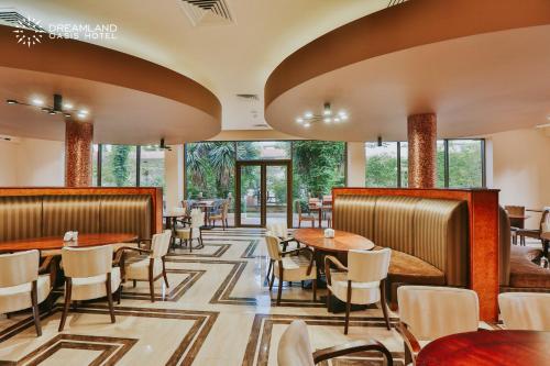a restaurant with tables and chairs and windows at Dreamland Oasis Hotel Chakvi in Chakvi