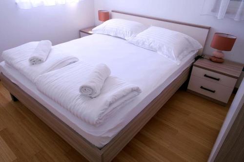 a bed with white sheets and pillows on it at Dalmatino - apartment 6 in Sutivan