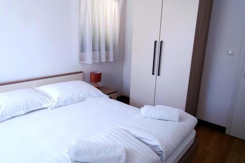 a bedroom with two beds with white sheets and a refrigerator at Dalmatino - apartment 6 in Sutivan