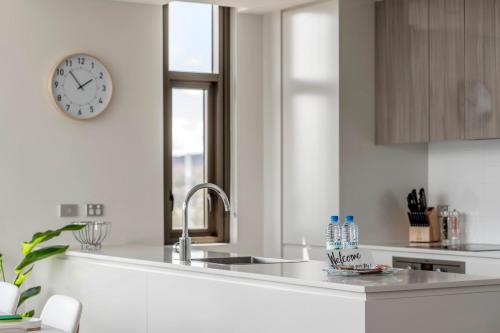 eine Küche mit einem Waschbecken und einer Uhr an der Wand in der Unterkunft Luxe 2 Bedroom Apartment in Barton in Kingston 