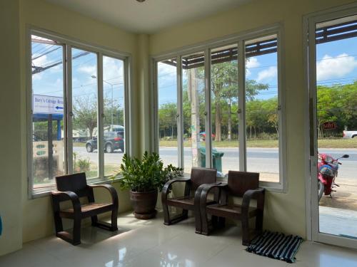 a room with windows with chairs and a plant at Andaman Place in Thalang