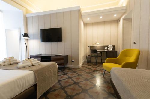 a hotel room with two beds and a chair and a desk at B&B Palazzo Perrotta in Catania