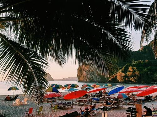 a beach with umbrellas and people sitting on the sand at Rinna Resort in Koh Mook