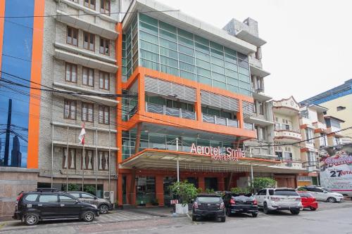 a large building with cars parked in front of it at Aerotel Smile Losari in Makassar