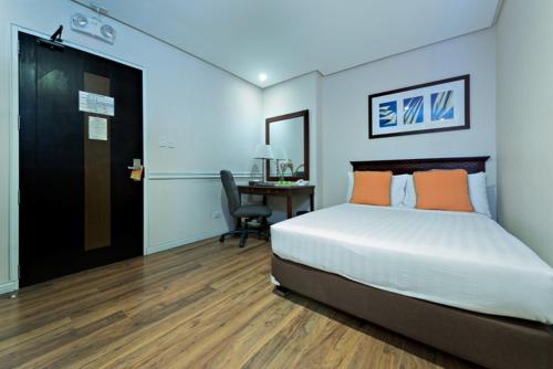 a bedroom with a bed and a desk with a chair at Court Meridian Hotel & Suites in Olongapo