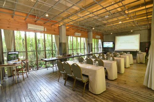 a conference room with tables and chairs and a projection screen at Greenhost Boutique Hotel Prawirotaman in Yogyakarta
