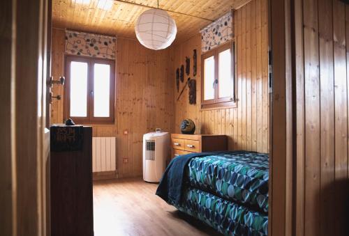1 dormitorio con 1 cama y nevera. en La cabaña del bosque en Villalba de la Sierra