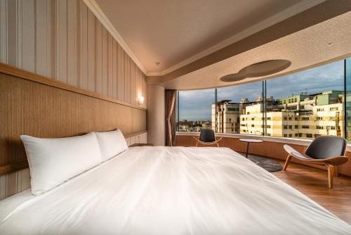Fish Hotel-Pingtung في بينغتونغ سيتي: غرفة نوم بسرير ابيض كبير ونافذة