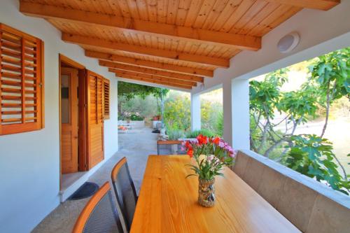 a wooden table with flowers in a vase on a porch at Getaway Beach House in Vela Luka