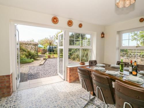 ein Esszimmer mit einem Tisch und Stühlen sowie einer Glasschiebetür in der Unterkunft Minffordd in Newborough
