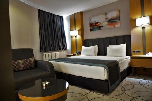 a hotel room with a bed and a couch at Ramada By Wyndham Nilufer Bursa in Bursa